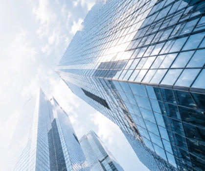 Modern glass office towers viewed from below against a bright sky
